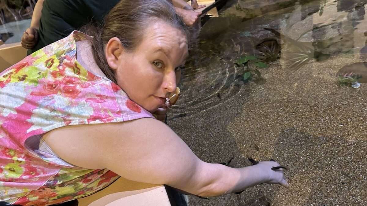 girl with hand in water touching sand