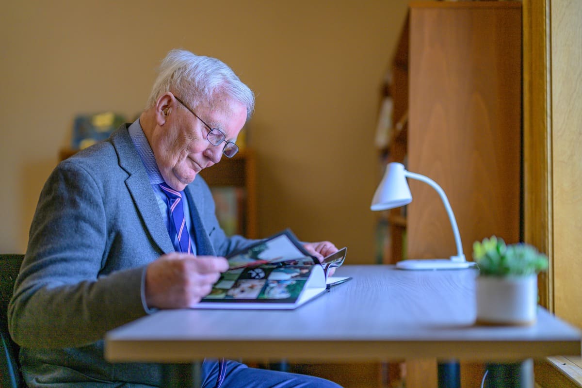 Older man reading a Easterseals VT book at a desk
